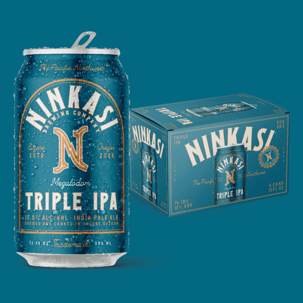 A teal-colored can and box of Ninkasi Brewing Company's "Megalodon Triple IPA" beer. The can is covered in condensation droplets, emphasizing its coldness. It features the brewery's logo, the location "Eugene, Oregon," and a mention of being established in 2006. The label showcases a strong 10.8% alcohol content and the beer's description as an India Pale Ale brewed and canned in Eugene, Oregon. The matching box in the background indicates a six-pack with branding details consistent with the can design.